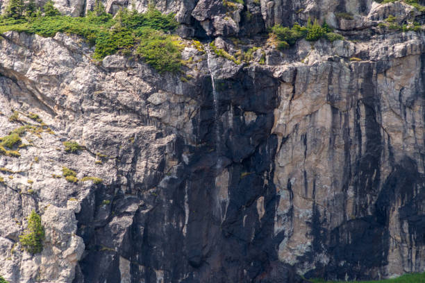 istock A seasonal waterfall cascading down a rugged cliffside surrounded by greenery on a sunny day in the mountains 2169634799