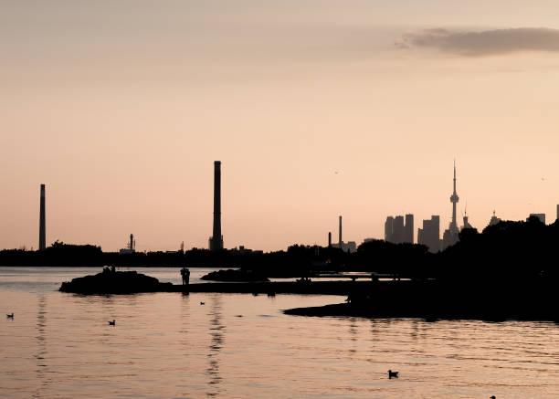 A stunning city skyline at sunset reflected in the calm waters of a lake.