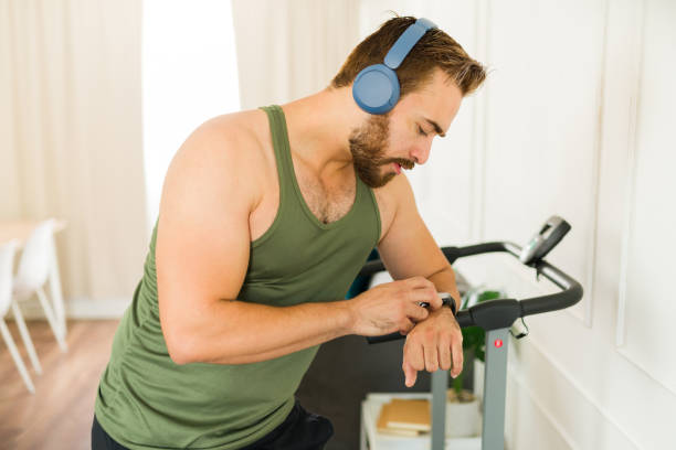 istock Active young man wearing sportswear setting smartwatch before starting a workout on a treadmill at home 2169652174
