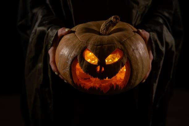 istock The witch is holding a pumpkin jack o lantern glowing in the dark. Halloween. 2169656528