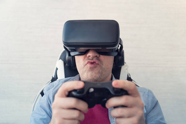 istock Modern technologies and domestic entertainment concept. Young man trying virtual reality at home, using headset VR glasses and holding joystick, playing video games 2169658273