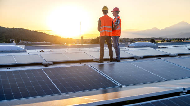 istock Caucasian Engineers Assessing Solar Panels on Rooftop at Sunset 2169658990