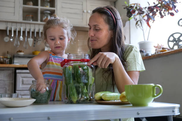 A young girl helping her grandma cut up cherries for a cherry angle food cake