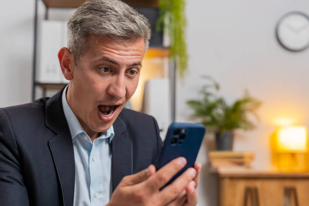 istock Happy amazed young Caucasian freelancer working on smartphone shocked by sudden victory at home 2169659556
