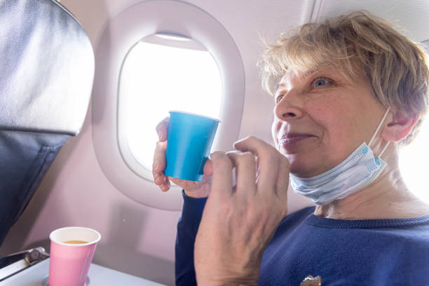 Drinking coffee in airplane. Mature Caucasian women drinking coffee during the flight.