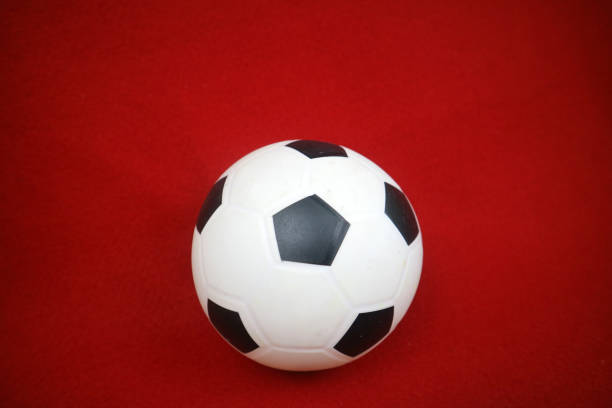 istock a small white and black toy rubber ball. Red background 2169673063