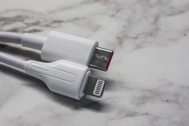 White cables for charging and synchronization with Type - C and Lightning connectors on a light background.