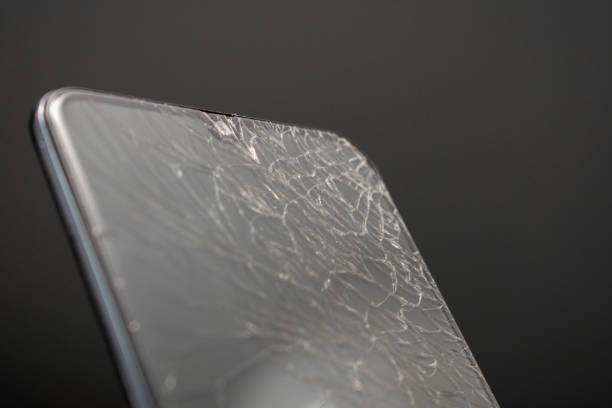 Black phone with a cracked screen set against a dark background. Highlights visible damage while emphasizing its current state.