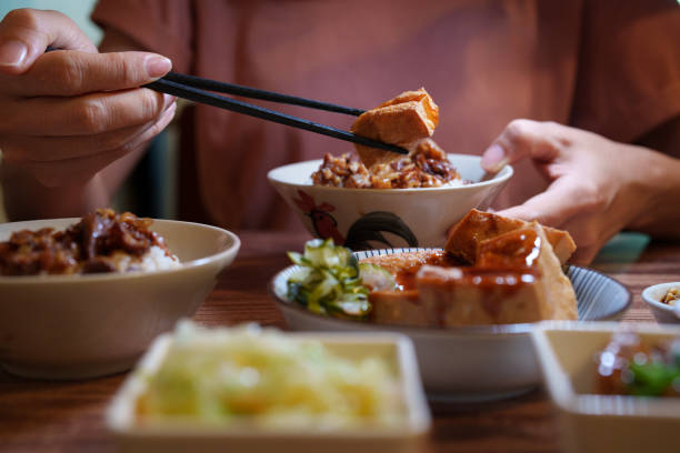 Close up shot of a young girl is seen enjoying a Taiwanese-style braised pork rice, soup, and side dishes. stock photo