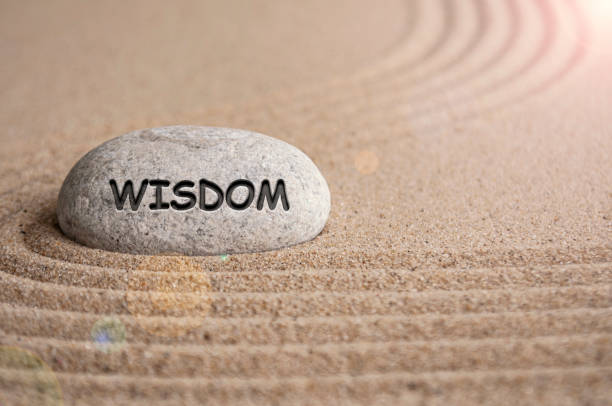 istock Wisdom text engraved on stone with sand beach background. Peace of mind concept. 2169679468