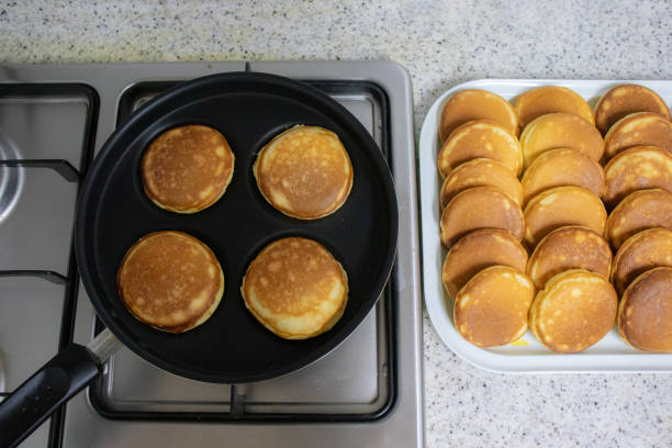 Cooking homemade fluffy pancakes in a 4-slot frying pan.