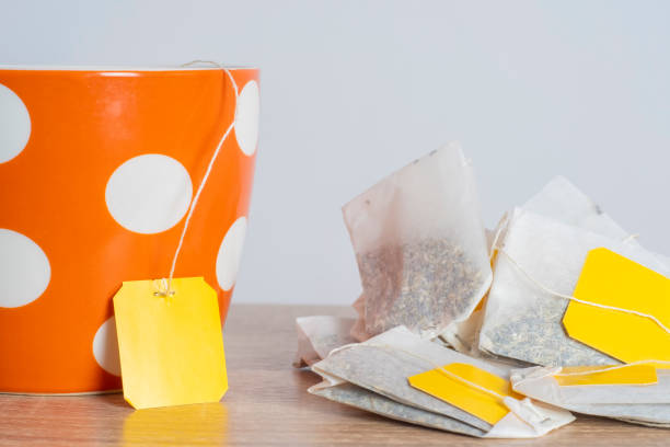 Putting tea bag into glass cup on white background, closeup