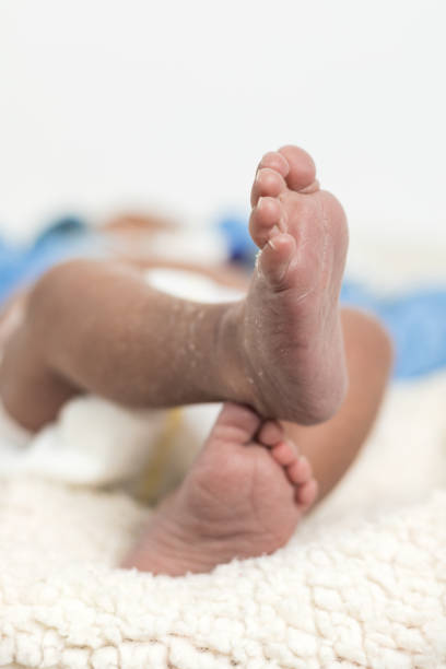 Unrecognizable close up of adorable newborn baby feet lying on soft blanket