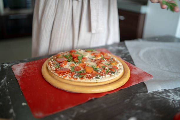 Woman in kitchen preparing dough for pizza