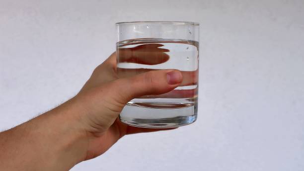 istock Hand holds a transparent glass with clean water. 2169702499
