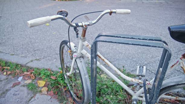 istock Abandoned Old Rusty Bicycle Secured with Lock Cable by City Bike Stand 2169704899