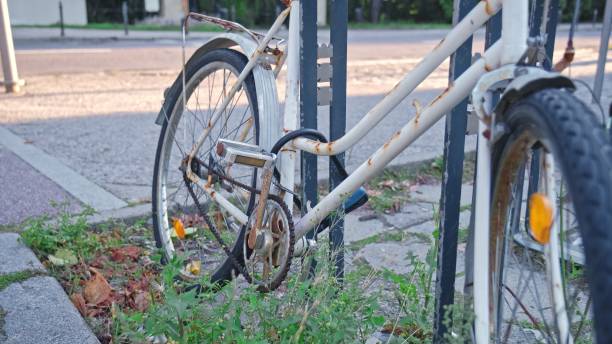 istock Abandoned Old Rusty Bicycle Secured with Lock Cable by City Bike Stand 2169704904