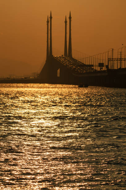 Sunrise over Penang Bridge with sunlight reflecting on the sea.