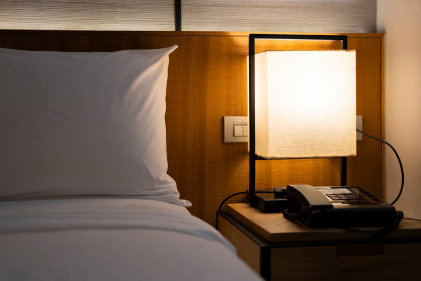 istock Modern Japanese style bedroom headboard with bed and pillows for sleeping and resting in a dim atmosphere with a bedside light on. Accommodation, hotel. 2169707953