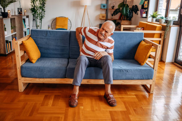 istock Old man feeling pain at home in living room while sitting on sofa 2169711721