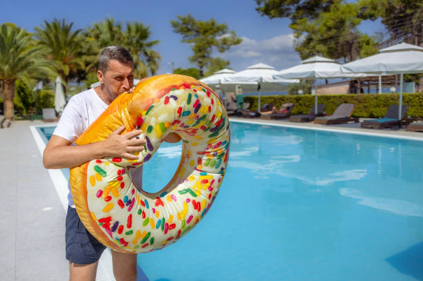 Mature man blowing up a float for a day of water fun on the pool