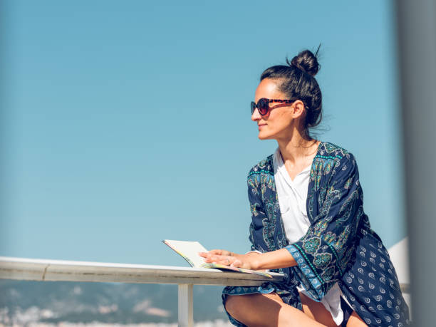 Happy woman with digital tablet and credit card buying online sitting near the sea.