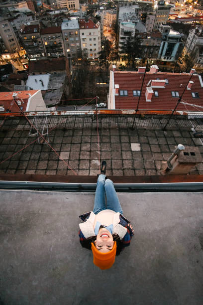 A young woman sitting on a rooftop in warm clothing on a cold winters day. Directly above perspective. Different perspective