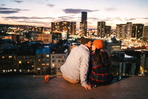 Couple drinking coffee  and kissing on a rooftop at night