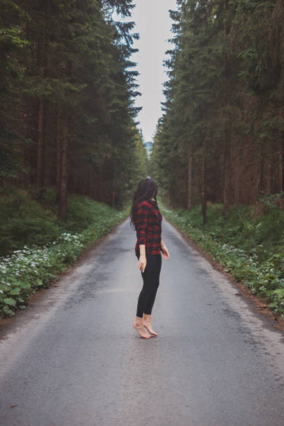 istock Brunette aged 20-25 in black leggings and a plaid shirt prances and dances on a forest path in a forest setting. The joy of movement and fresh air. Forest Fairy 2169727403