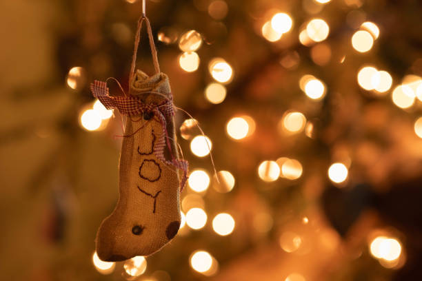 istock Simple, rustic Christmas ornament hung on lit tree with holiday light bokeh effect. 2169733075