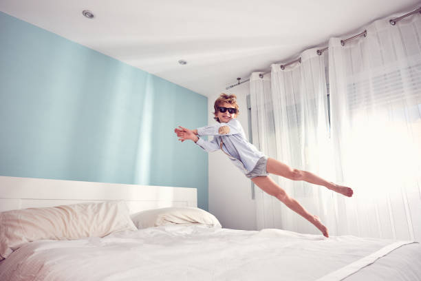 istock Joyful boy jumping on bed in morning 2169733551