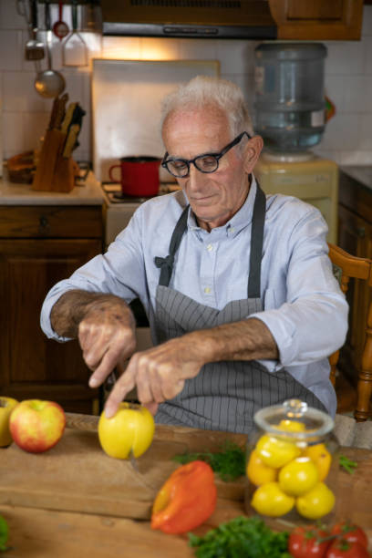 istock Elderly Hand Cutting a Yellow Apple in a Rustic Kitchen 2169733785
