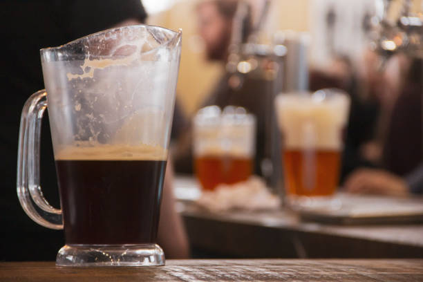 istock Half empty pitcher of dark ale inside a busy bar. 2169734097