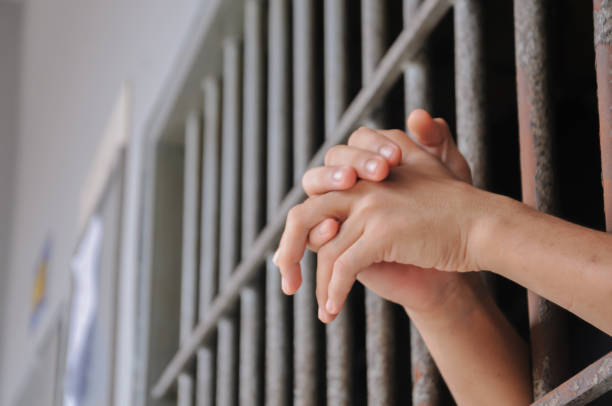 istock Hands of a prisoner behind prison bars 2169735289