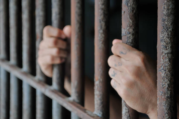 istock Hands of a prisoner behind prison bars 2169735307
