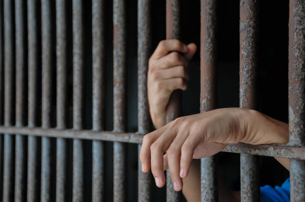 istock Hands of a prisoner behind prison bars 2169735325