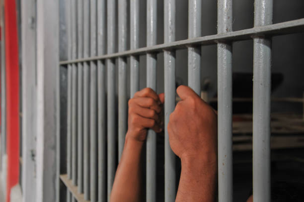 istock Hands of a prisoner behind prison bars 2169735476