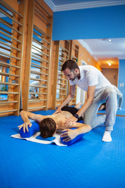 istock The boy is doing kinesiotherapy exercises with the chiropractor helping him. Exercises for correcting the spine and pelvis, scoliosis. 2169735704