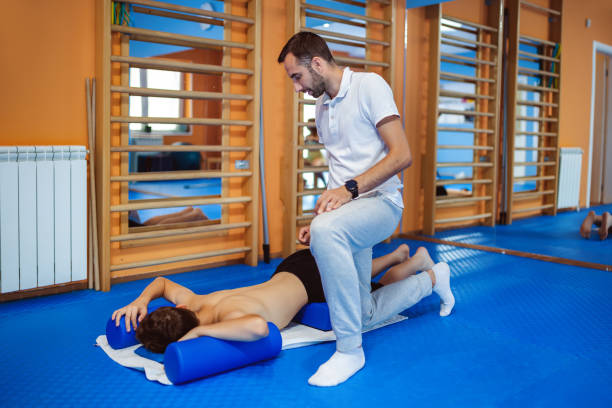 istock The boy is doing kinesiotherapy exercises with the chiropractor helping him. Exercises for correcting the spine and pelvis, scoliosis. 2169735710