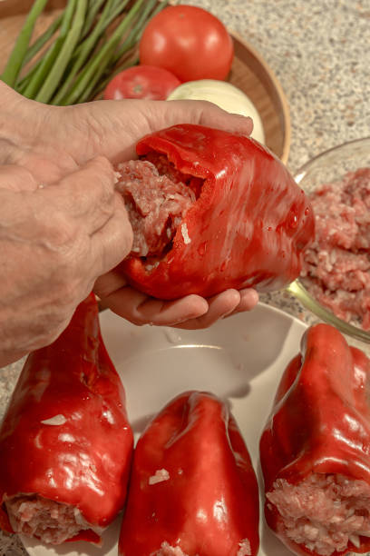 istock Cook stuffs a seeded red bell pepper with raw minced meat. Close-up 2169737393