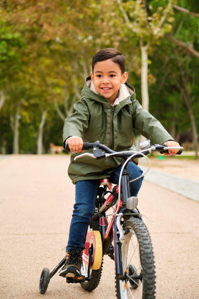 istock Latin five years old boy riding his bicycle in a park in a fall day. 2169742747