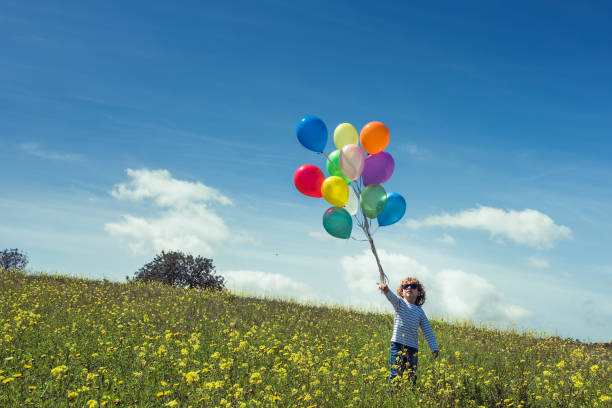 istock Boy with balloons in green field 2169744147