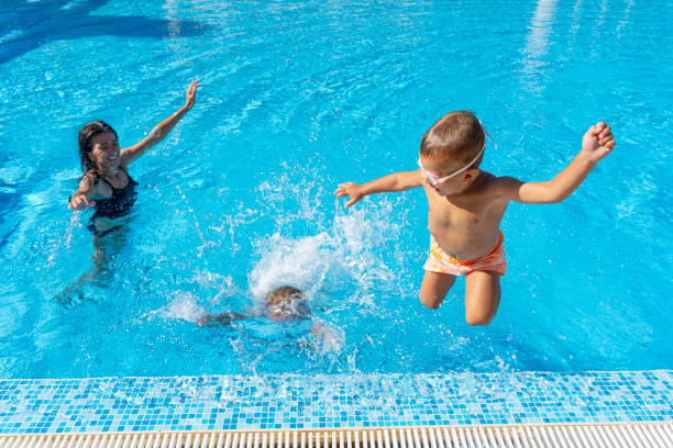istock Kids jumping into a swimming pool on a sunny day 2169752281