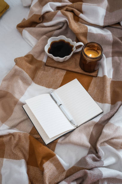 istock A beautiful, cozy scene featuring a warm cup of coffee, a notebook, and a flickering candle 2169752697