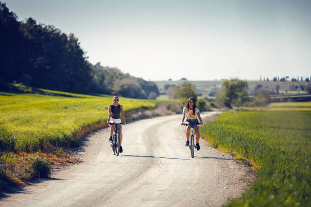 istock Young women friends cycling while clapping their hands through rapessed field 2169756692