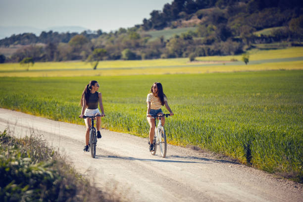istock Young women friends cycling while clapping their hands through rapessed field 2169757035