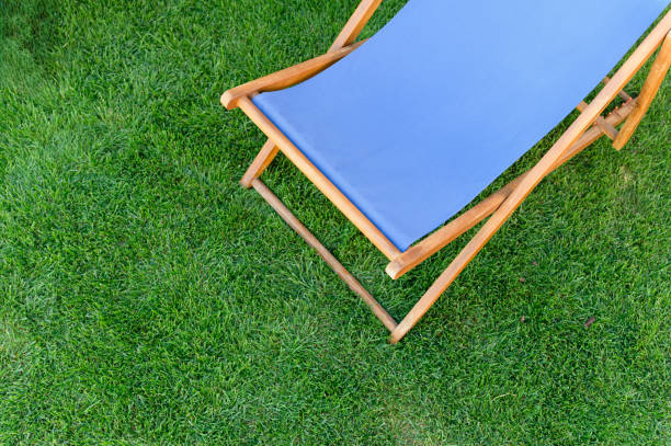 istock Deck chair with blue fabric on green grass background. 2169763207