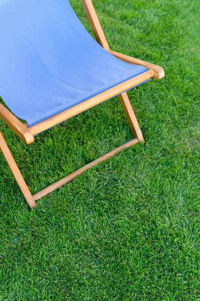 istock Deck chair with blue fabric on green grass background. 2169763213