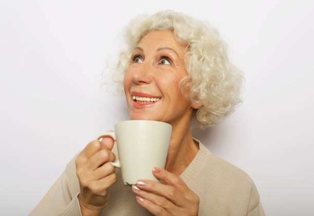 istock old excited lady smiling laughing, holding cup drinking coffee, tea, beverage on white background 2169767366