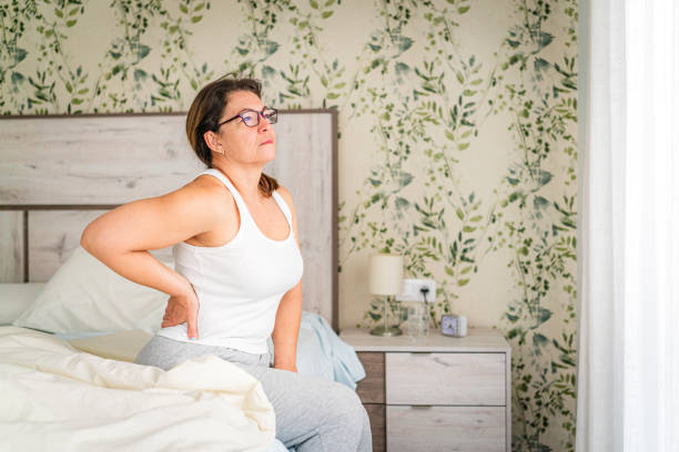 istock Woman sitting on bed suffering backache 2169769405